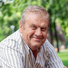 Natural Pharmaceuticals Hepactum FORTE Idős férfi mosolyogva ül parkban, zöld háttérrel, napsütésben.